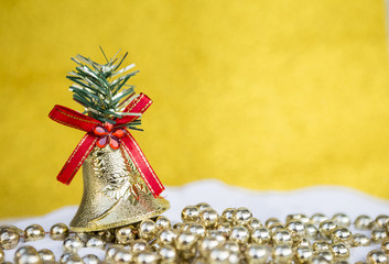 Christmas background concept, Design Christmas bell on shiny beads over blurred yellow background