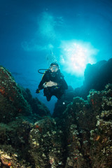 woman scuba diving over rocks in the Mediterranean Sea