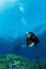 Fototapeta na wymiar woman scuba diving over rocks in the Mediterranean Sea