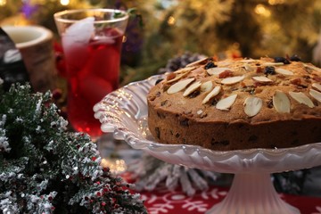 Xmas Dundee fruit cake with christmas tree in background, selective focus