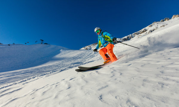 Young skier running downhill in beautiful Alpine landscape.