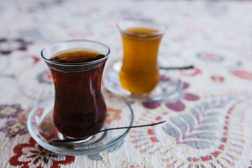 Two traditional Turkish teas with tulip mugs stand side by side on the table. Spoons are on the saucers. Delicious and healthy drink.