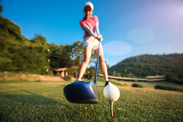 wood driver and golf ball in Addressing the ball by woman golf player, ready to hit away from tees...