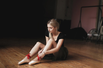 Fototapeta na wymiar Beautiful ballerina sitting on floor
