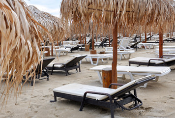 sandy beach with thatched umbrellas and sunbeds for your design