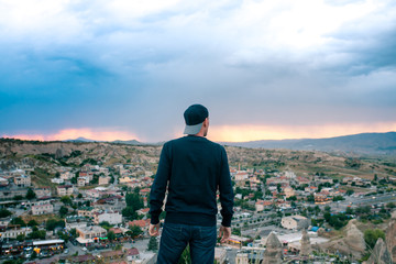 Young man tourist from a high point looking at the sunset over the city of Goreme in Cappadocia in...