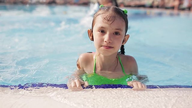 Little girl having fun in a swimming pool, first time learning to swim, spending summer holidays on a beach resort
