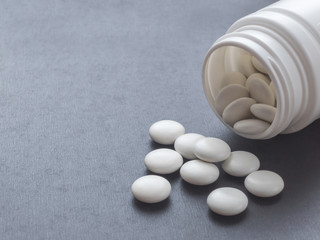 Round white pills spilled from a white bottle. Dope. Vitamins