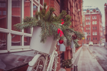 Street Christmas decorations - a branch of a pine tree with toys on a background of a red brick wall