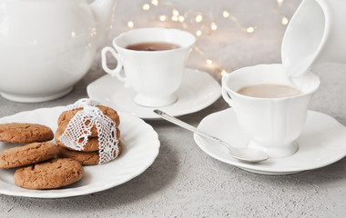 Close-up of white cups of coffee with milk and chocolate cookies on table in vintage style background