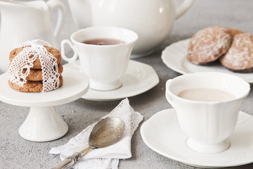 Close-up of white cups of coffee with milk and chocolate cookies on table in vintage style background