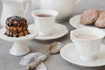 Close-up of white cups of coffee with milk and chocolate cookies on table in vintage style background