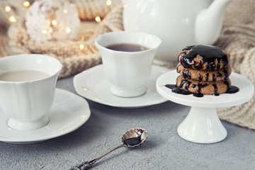 Close-up of white cups of coffee with milk and chocolate cookies on table in vintage style background