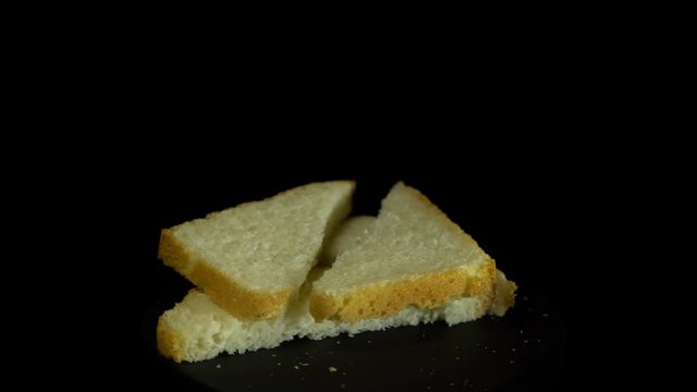 Close-up of sliced white wheat bread rotates against a black background, loopy motion.