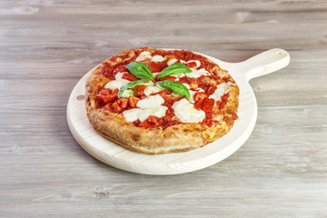 italian gourmet pizza on wooden chopping board. Focaccia with tomato sauce, basil and mozzarella