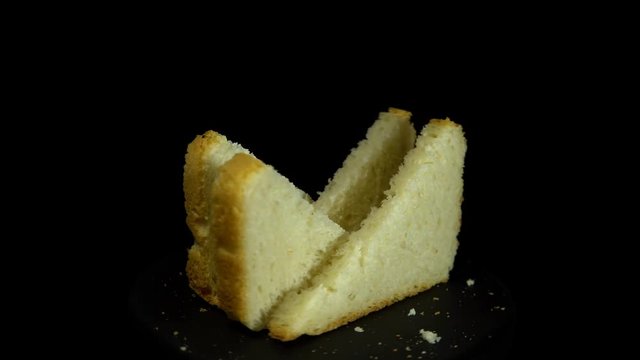 Close-up of sliced white wheat bread rotates against a black background, loopy motion.