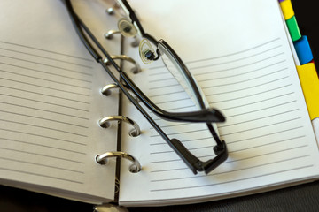Notebook, spiral notepad macro, close up. Selective focus. Black glasses.