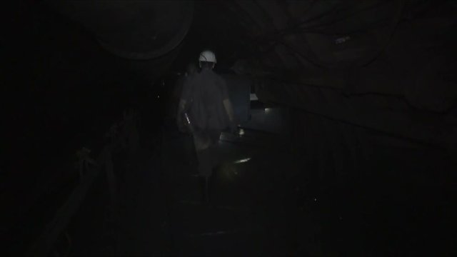 Miners in the coal mine walk along the tunnel