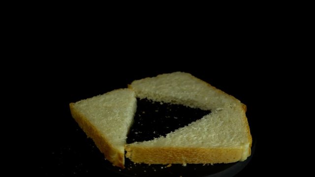 Close-up of sliced white wheat bread rotates against a black background, loopy motion.