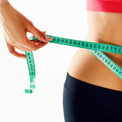Woman measuring her waist over white background. Wellness concept.