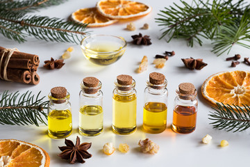 Selection of essential oils with Christmas spices on a white background
