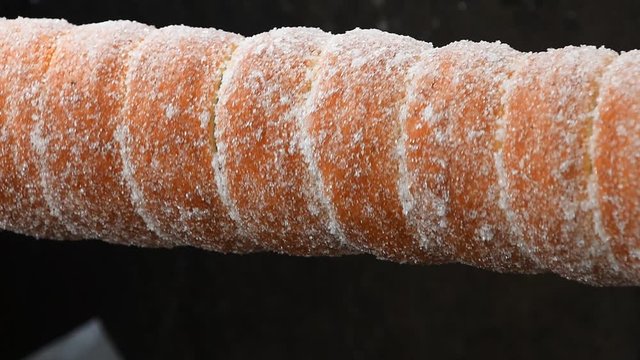 Close up sweet Trdelnik baking on grill and rolling, this spit cake is popular in Europe, Austria, Hungary, Slovakia and Czech, especially in Prague