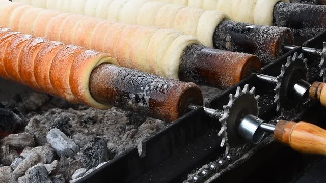 Close up sweet Trdelnik baking on grill and rolling, this spit cake is popular in Europe, Austria, Hungary, Slovakia and Czech, especially in Prague