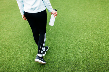 Obraz premium Running girl holding a bottle of water. The girl made a break, after a good workout.