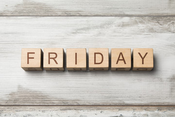 Fototapeta premium FRIDAY word written on wooden cubes on wooden background