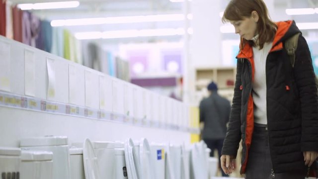 Young woman is choosing lavatory pan at shop
