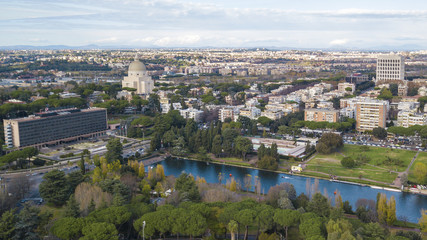 Fototapeta na wymiar Vista aerea del moderno quartiere dell' EUR a Roma, costruito per l'Esposizione universale che si sarebbe dovuta tenere nella Capitale nel 1942. In primo piano il piccolo lago e il parco del quartiere