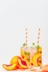 Peach lemonade with ice and mint leaves. Homemade lemonade of ripe nectarine with white and orange...