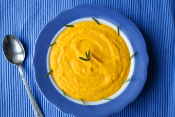 pumpkin cream soup in a blue plate on blue napkin.