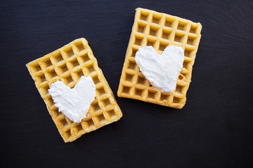 Delicious belgian waffles with cream on a black background