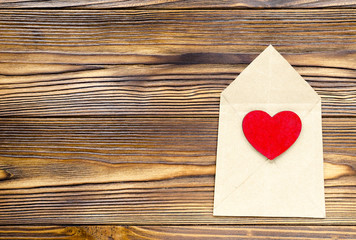 kraft paper envelope with wooden red heart on wooden table with copy space