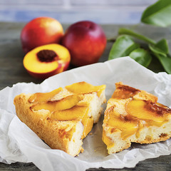 A pie with nectarines on a gray wooden table.