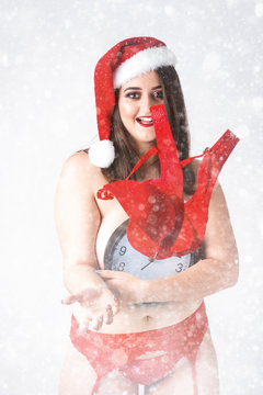 Christmas New Year concept countdown to midnight. Model XXL in panties with clock. Fat woman with naked breast. Happy plus size girl drop bra. Big Female in santa claus hat with snowflakes