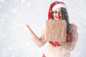 Christmas New Year concept of selling gifts. Model XXL in lingerie with presents. Fat woman in underwear. Happy plus size girl buy gift with discount. Big Female in santa claus hat with snowflakes