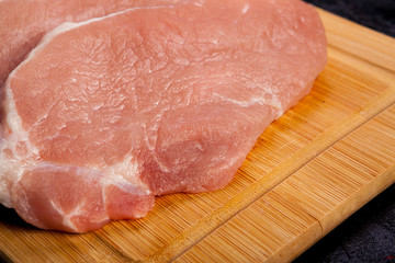 Close up on Fresh raw meat on wooden board on black wooden background. Gourmet food and fresh uncooked meal