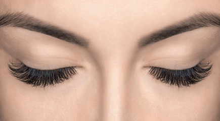 Eyelash extension procedure. Beautiful Woman with long lashes in a beauty salon.