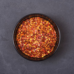 Chili powder spice in a bowl on a grey concrete background