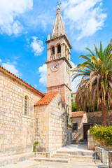 Fototapeta na wymiar Church building and palm tree against sunny blue sky in Splitska village on Brac island, Croatia