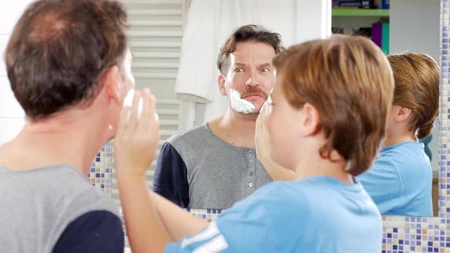 Father letting son putting shaving cream on his face funny