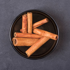 Cinnamon sticks in a bowl on a grey concrete background