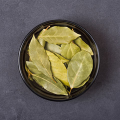 Bay leaves in a bowl on a grey concrete background