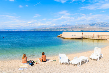 Two unidentified young women relaxing on beautiful beach in Postira village, Brac island, Croatia