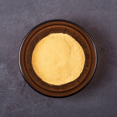Cinnamon powder in a bowl on a grey concrete background