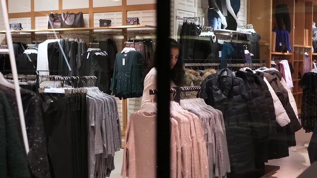 Attractive young woman shopping for clothes, browsing wardrobe