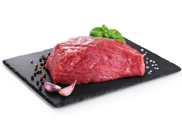 Raw fresh meat, pepper, basil and garlic on the background of a slate board.