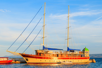BOL TOWN, CROATIA - SEP 7, 2017: Traditional wooden yacht boat anchoring in Bol port at sunset time, Brac island, Croatia.